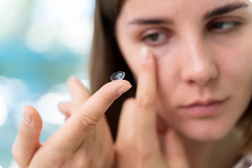 Hands cleaning gas permeable contact lenses with saline solution for safe use.