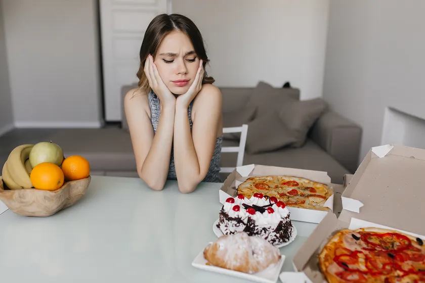 Woman frustrated by unhealthy food choices, contributing to what is constipation and digestive issues.