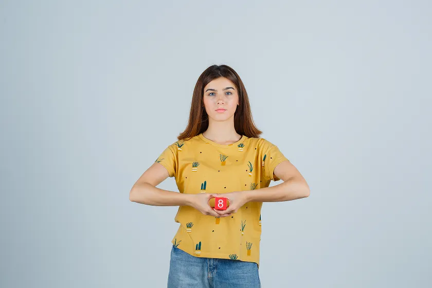 Woman holding the number 8, symbolizing the importance of fiber intake to prevent what is constipation.