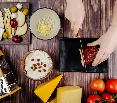 Hands slicing meat with cheese and the keto diet ingredients