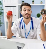 Doctor choosing between apple and donut for healthy eating
