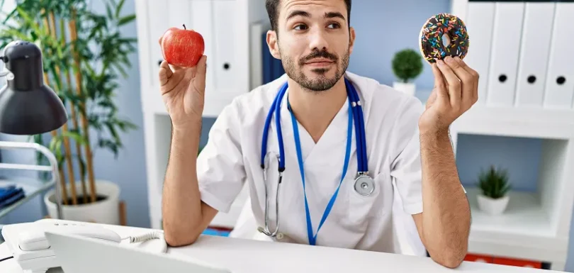 Doctor choosing between apple and donut for healthy eating