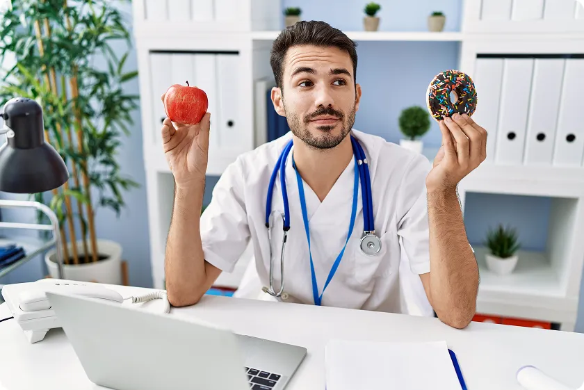 Doctor choosing between apple and donut for healthy eating