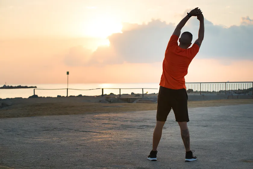 Man stretching at sunrise for how to stay active throughout the day