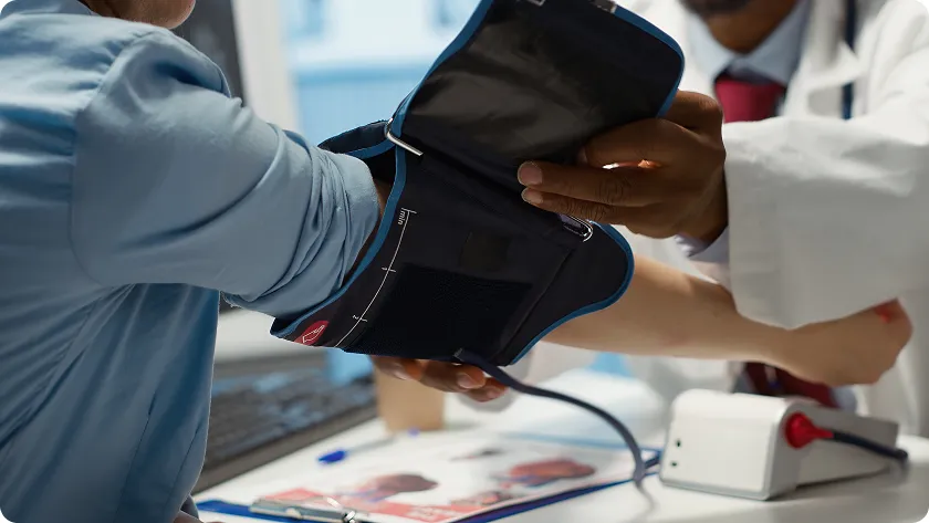 Close-up of doctor applying cuff to show the difference between hypertension and hypotension.