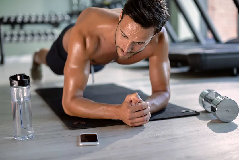 Weekly workout plan for men performing plank with dumbbells