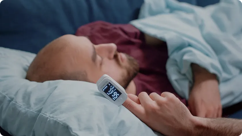 Pulse oximeter checking cardiovascular levels and oxygen saturation for a sleeping man.
