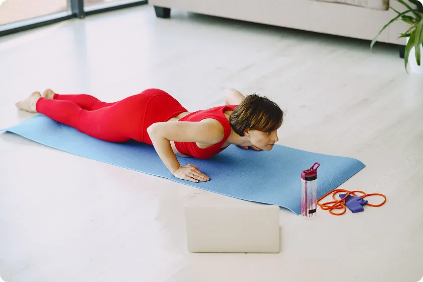 Woman doing cobra push-up at home following arm workouts without equipment routine.