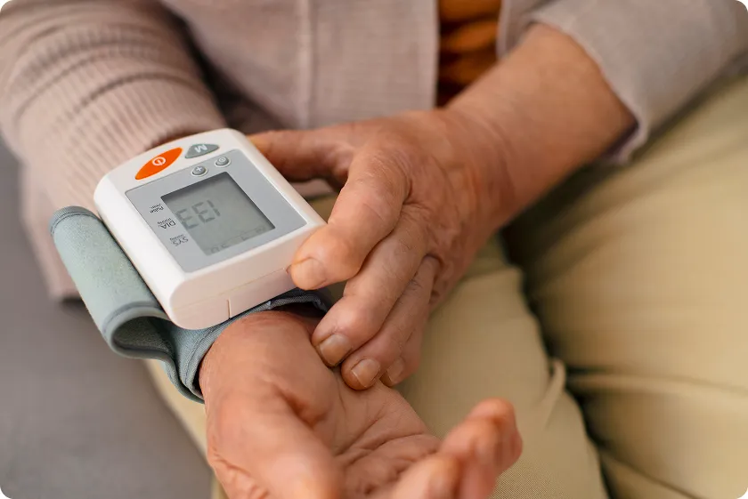 Senior using a wrist monitor to check heart index and blood pressure levels.