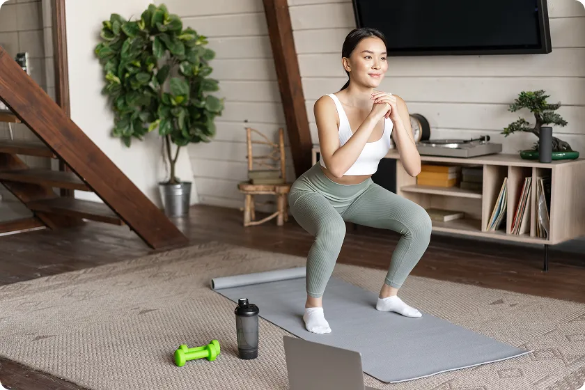 Woman doing squat on mat at home for bodyweight-exercises and leg training.