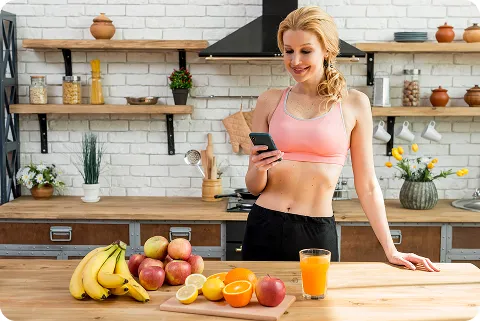 Woman checking phone while prepping fruits for ketovore diet breakfast
