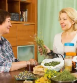 Two women discussing herbal teas and natural remedies for constipation at a table.