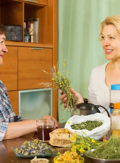 Two women discussing herbal teas and natural remedies for constipation at a table.