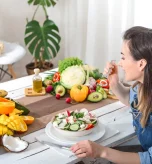 Woman eating fresh salad with fruits and vegetables demonstrating gout exercise and healthy diet