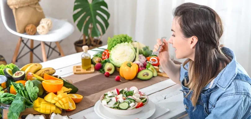 Woman eating fresh salad with fruits and vegetables demonstrating gout exercise and healthy diet