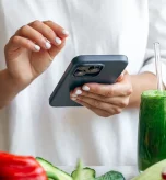 Person holding a smartphone near healthy food during a social media detox.