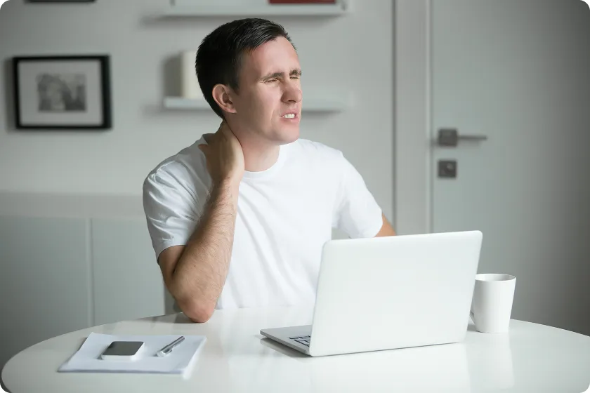 Man at his desk experiencing left side neck and shoulder pain and sudden neck strain symptoms.
