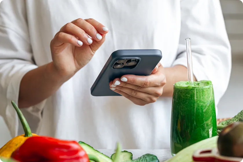 Person holding a smartphone near healthy food during a social media detox.