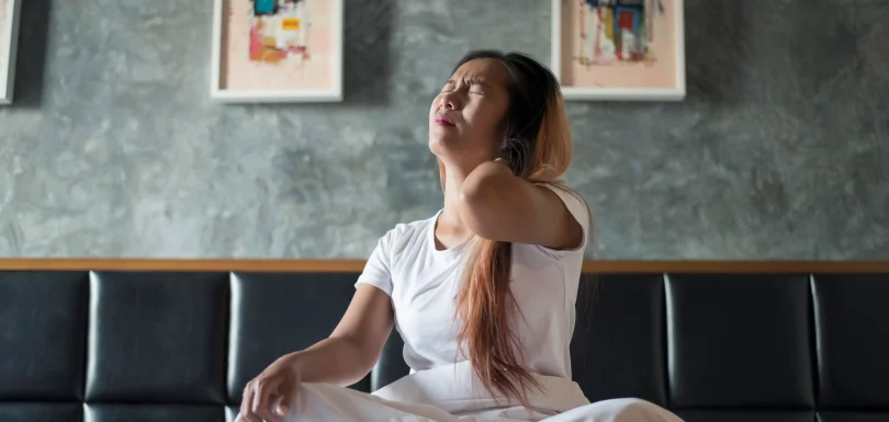 A woman waking up in bed with an expression of intense joint pain at night.