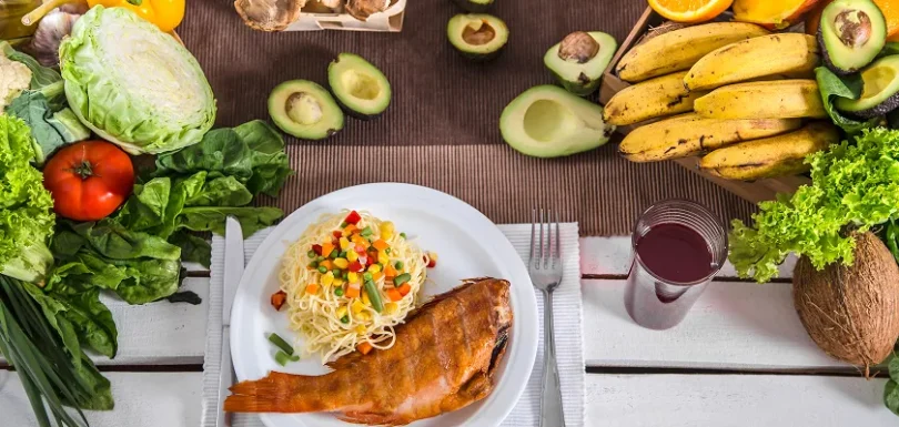 Table spread featuring cooked fish and pasta as foods good for diverticulitis.