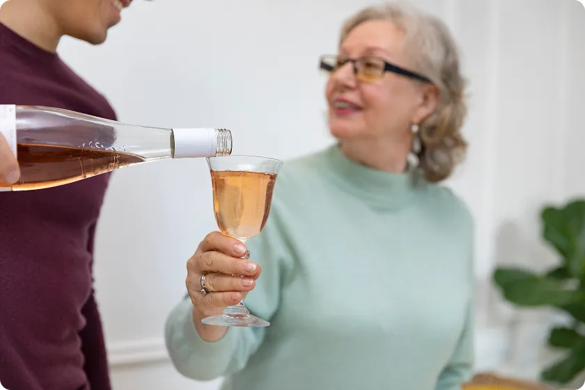 Wine poured for older woman, exploring how much alcohol is excessive