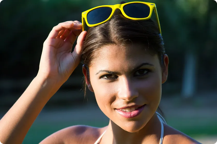 Woman wearing yellow shades shows uv protection of sunglasses outdoors