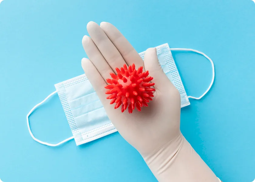 Gloved hand holds virus model near mask for norovirus testing