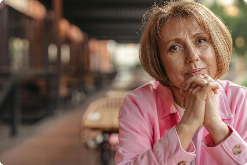 A middle-aged woman sitting calmly outdoors, reflecting on improving her lupus longevity through healthy habits.