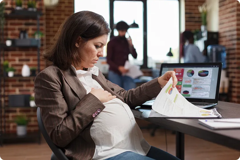 Pregnant woman over 35 managing a high-risk pregnancy while working at her desk.