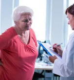 Older woman discussing menopause hip pain with her doctor during a clinical consultation.