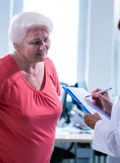2 Older woman discussing menopause hip pain with her doctor during a clinical consultation.
