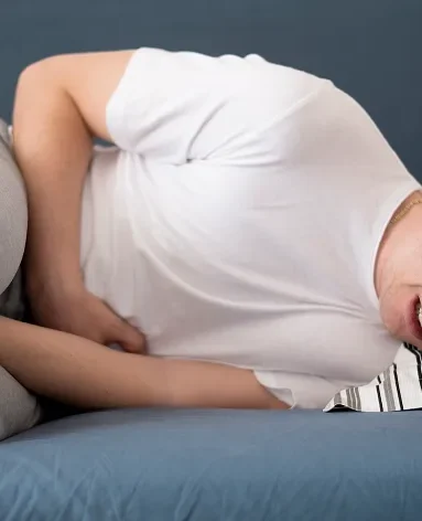 Man lying down in pain, illustrating common lupus nephritis symptoms and discomfort.