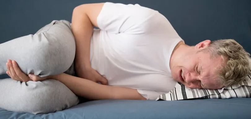 Man lying down in pain, illustrating common lupus nephritis symptoms and discomfort.
