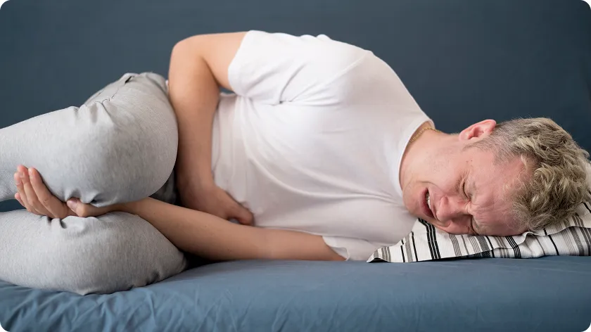 Man lying down in pain, illustrating common lupus nephritis symptoms and discomfort.