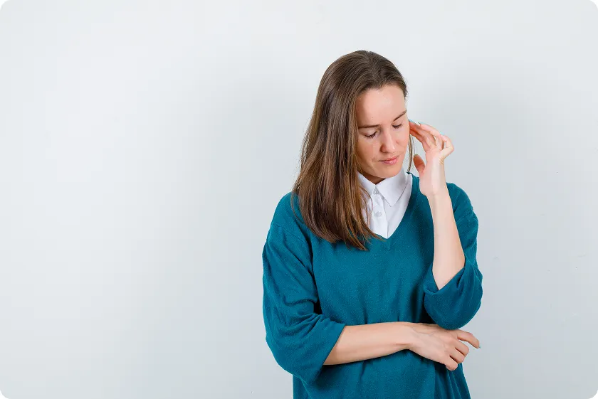 Concerned woman touching her ear while researching common signs of lupus.