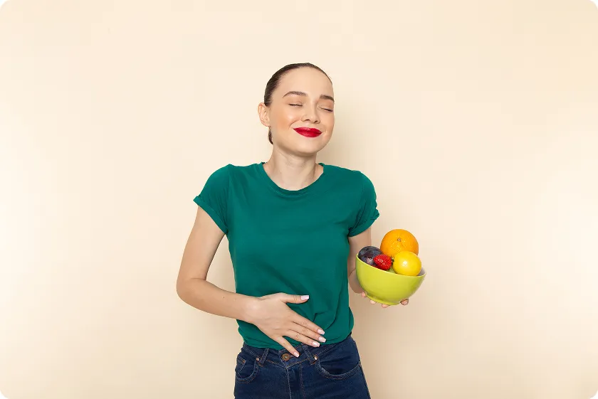 Woman holding fruit bowl feeling relief using a diet for diverticulitis flare up.
