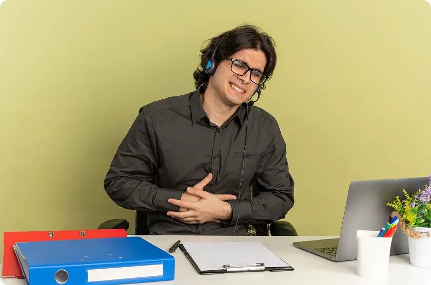 Remote worker grimacing from nausea and gerd beside laptop