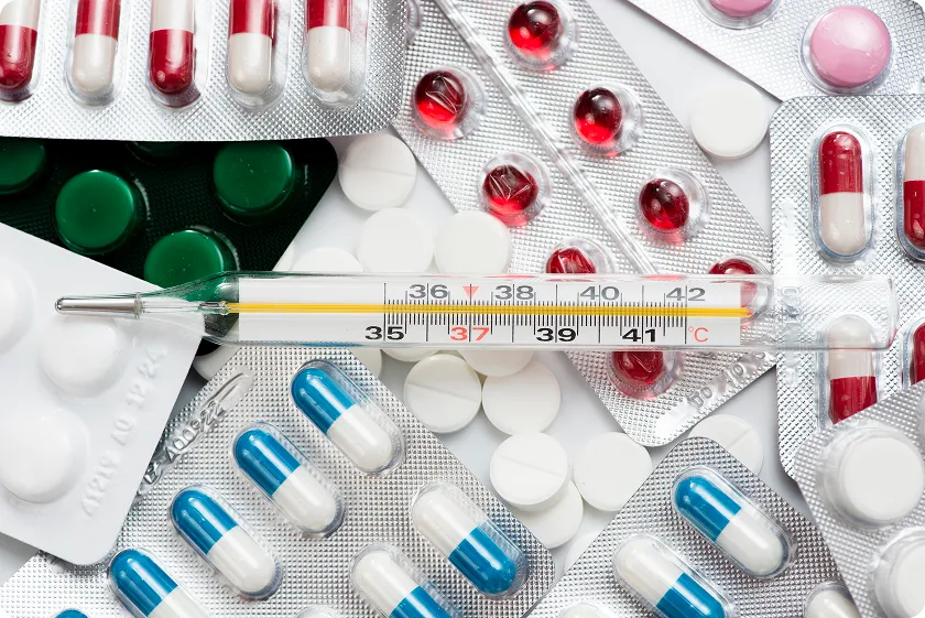 Assortment of pills and thermometer illustrating medication management for statin intensity chart.