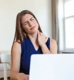 Woman working on a laptop suffering from a burning sensation back of neck and pain when turning head.