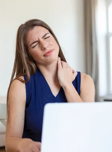 Woman working on a laptop suffering from a burning sensation back of neck and pain when turning head.