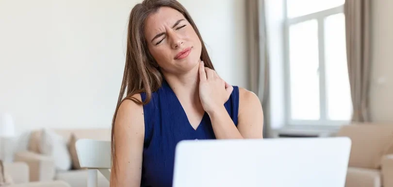 Woman working on a laptop suffering from a burning sensation back of neck and pain when turning head.