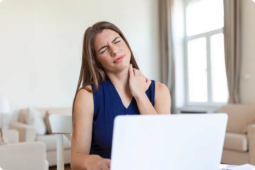 Woman working on a laptop suffering from a burning sensation back of neck and pain when turning head.