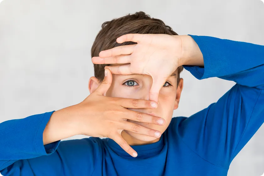 Child frames eye with hands before choosing protective uv glasses