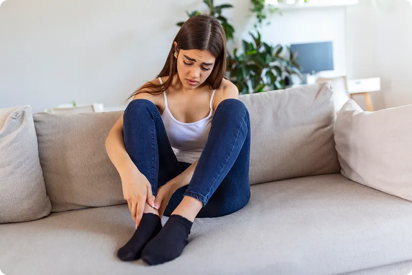 Concerned woman inspecting her ankles to look for heart failure swollen feet signs.