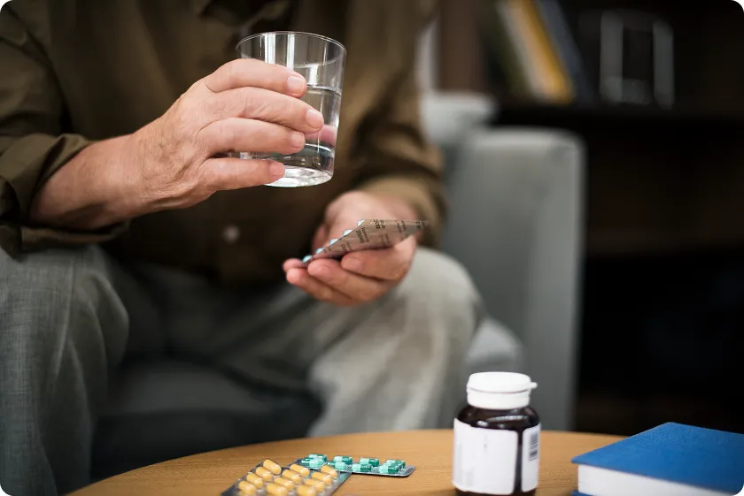 Patient holding water and taking pills following statin potency chart instructions for dosage.