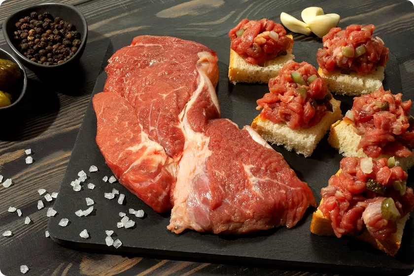 Raw beef cuts beside toppings for calories in 90/10 ground beef