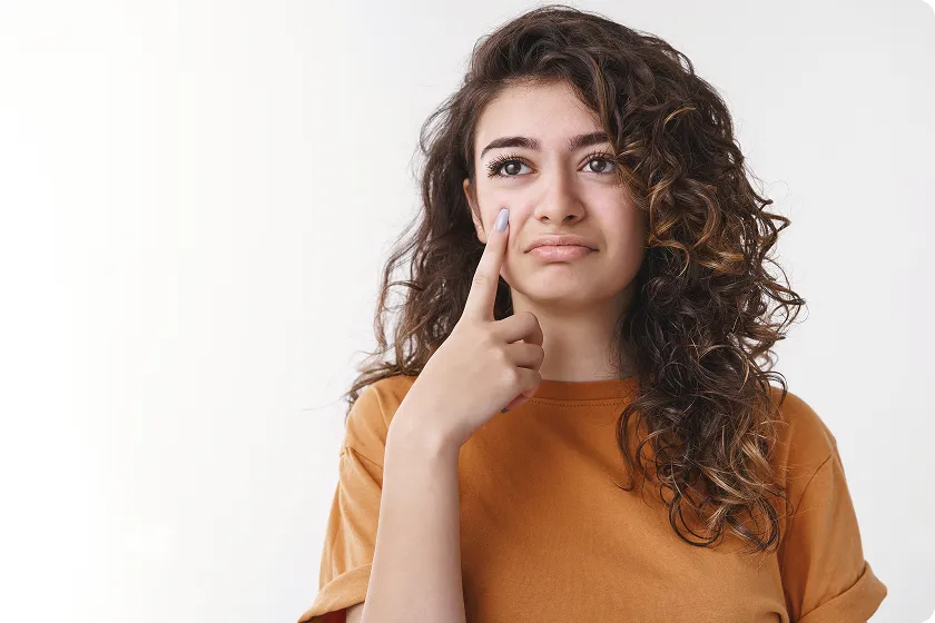 Woman checking cheek, explaining infection vs disease from harmful microorganisms.