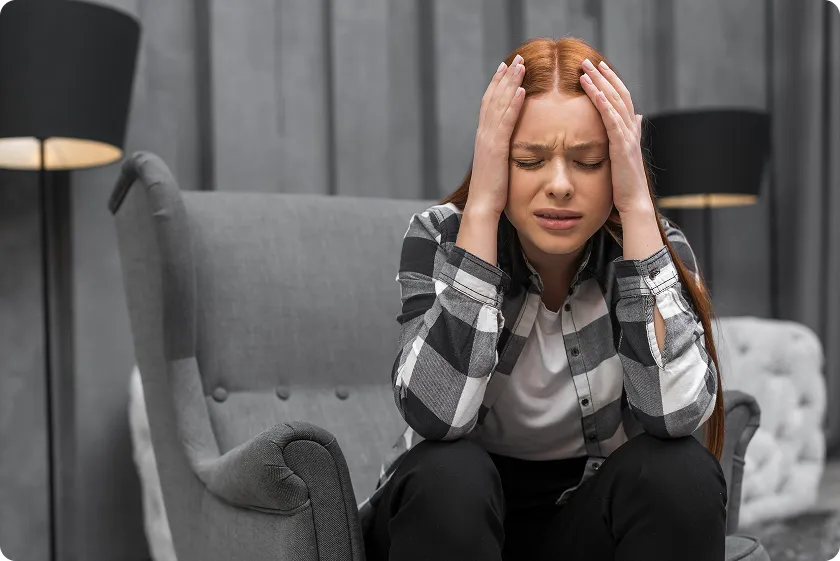 Woman sitting on a chair clutching her head with congestive heart failure symptoms women experience.