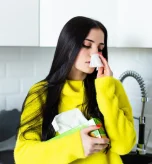 Sick woman uses a tissue in the kitchen detailing what are nasal polyps.
