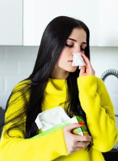 Sick woman uses a tissue in the kitchen detailing what are nasal polyps.